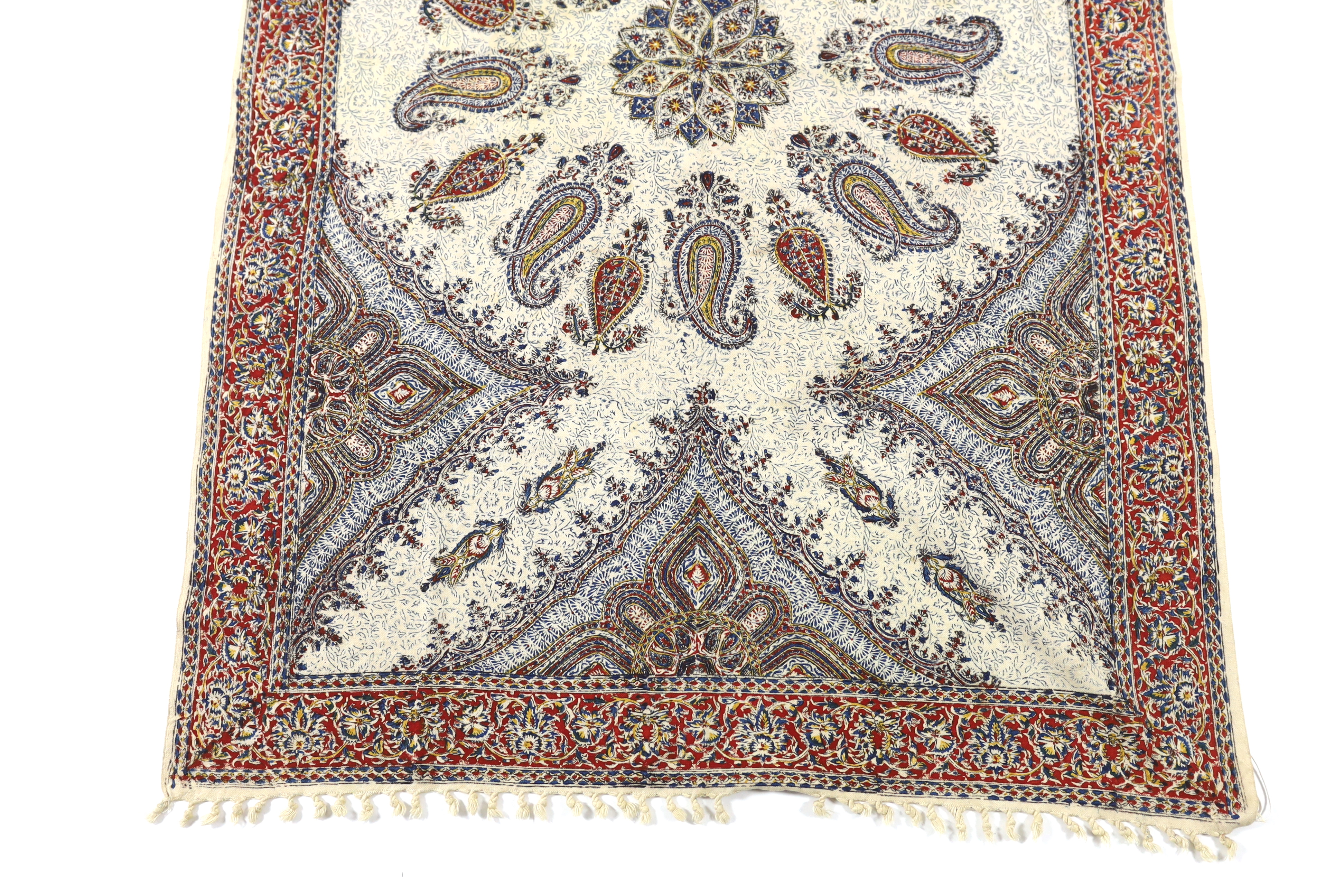 A 20th century Iranian printed paisley shawl, designed using indigo, red and ochre dyes, finished with knotted tassels either end, with an ink maker’s stamp on reverse, 148cm long x 100cm wide